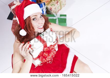 Smiling Sexy Caucasian Ginger Santa Helper Girl with Plenty of Colorful Present Boxes. Posing Against White Background. Horizontal Image