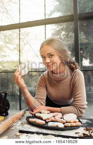 Beautiful smiling confectioner holding bitten heart. Young attractive woman looking at camera with traditional valentine treat, free space. Homemade bakery, sweet pastry, winter holiday, love concept