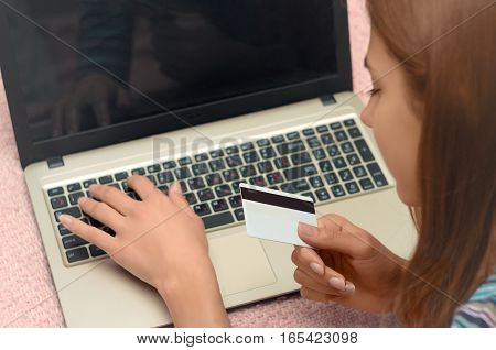 Closeup hand of girl typing credit card details on laptop to complete payment process. Close up of female hand paying bills online with laptop and credit card. Internet banking.