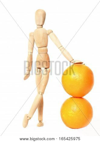 Wooden doll and oranges on a white background. The wooden dummy leans a hand on two oranges. It is isolated on white