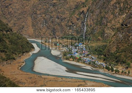 Scene in the Annapurna Conservation Area Nepal. Turquoise Marsyangdi river. Colorful houses of Tal. Waterfall.