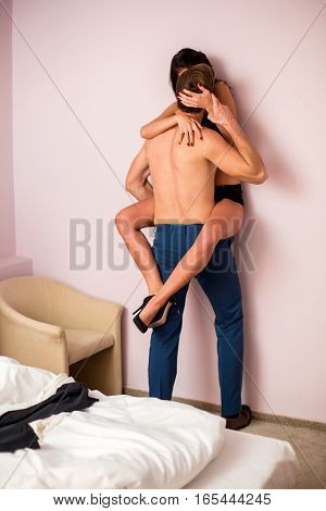 Young couple kissing against wall. Woman and man near bed. Relieve my stress.