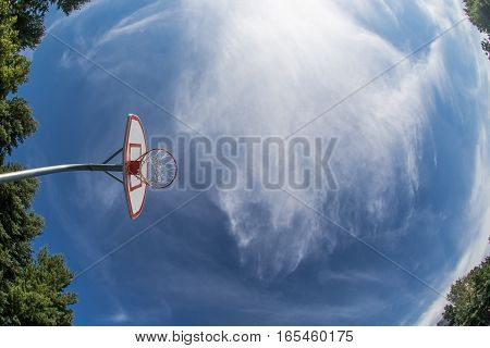 A suburban basketball hoop against blue sky.