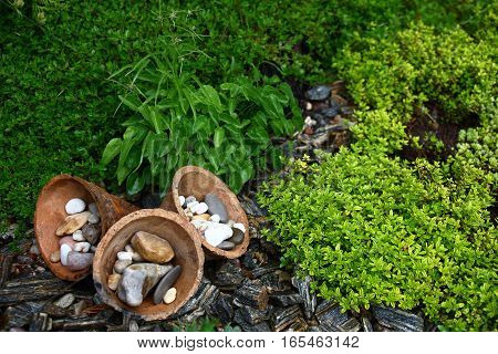 In a flower bed three ceramic cones and different small stones are used as decorative elements.