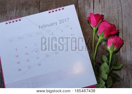 Close up calender with the date of 2017 February 14 Valentine's day and beautiful red roses on wooden board background