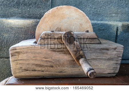 Close-up of old primitive grinding stone with wooden mechanism