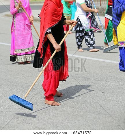 Many Barefoot Women With Colorful Clothes Sweep The Paved Road A