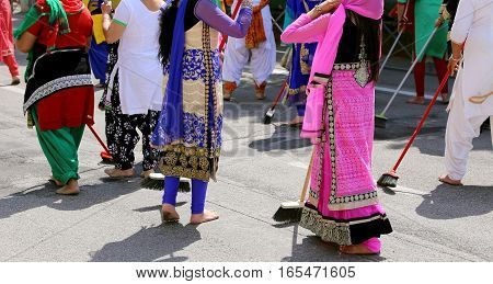 Women With Colorful Clothes Sweep The Asphalt Road During The Ev