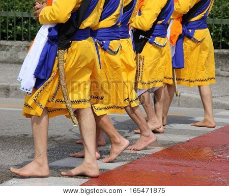Five Men With Long Dresses Walking Barefoot Through The Streets