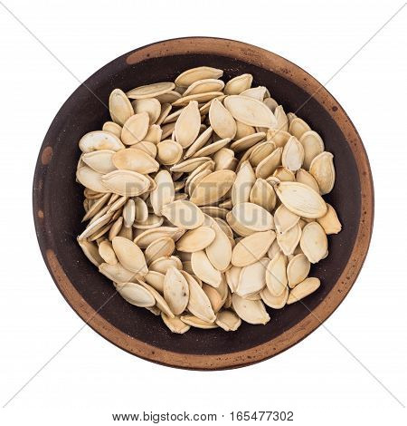 Pumpkin seeds in bowl isolated on white. Top view.
