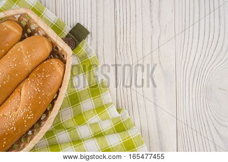 Buns in a wicker basket on old wooden table. Top view.