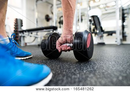 Close up of arm and legs of senior man in gym working out with weights