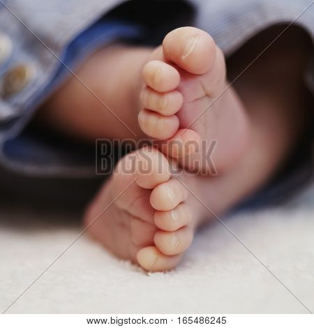 bare feet of newborn baby in jeans