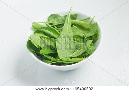 Arugula Leaves into a bowl over a white background