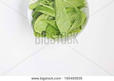 Arugula Leaves into a bowl over a white background