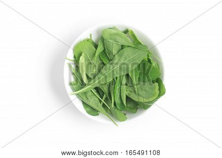 Arugula Leaves into a bowl over a white background