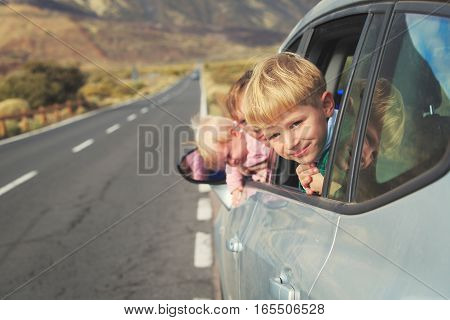 family travel by car- happy father with kids driving car on road in mountains