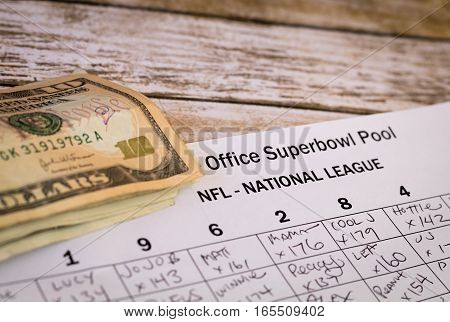 Office Superbowl Pool grid completed with money wager on wooden board