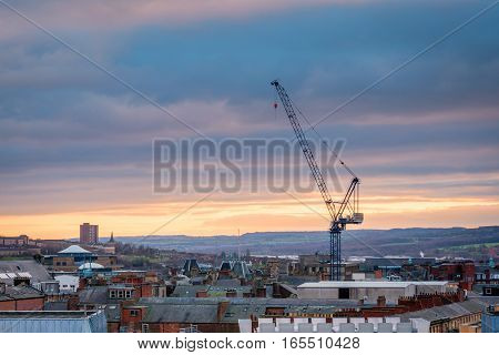 Tall Crane in Newcastle Skyline, in the city centre, towers above the rooftops as the sun sets