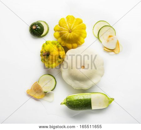 Yellow, white and green zucchini, courgette and round pattipan squashes isolated on white background. Sorts of sliced cucurbit top view