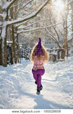 Beautiful woman doing yoga outdoors in the snow at winter time