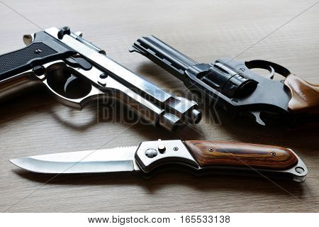 Black revolver pistols with knife on wooden board.