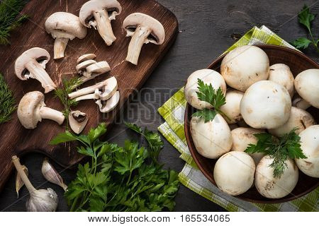 Sliced mushrooms and ingredients for cooking at dark wooden table. Space for text. Ingredients for cooking food background.