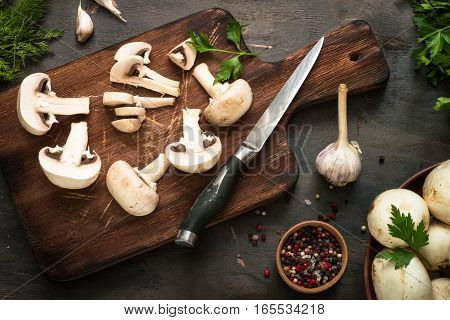 Sliced mushrooms and ingredients for cooking at dark wooden table. Space for text. Ingredients for cooking food background.