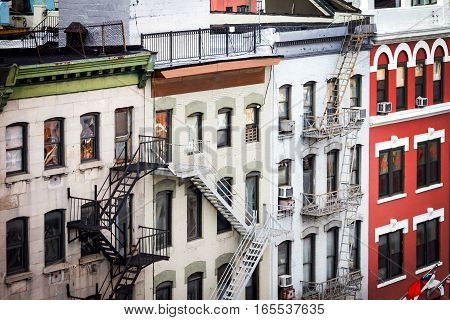 New York City view of historic apartment buildings with windows rooftops and fire escapes along Bowery street in the Chinatown neighborhood of Manhattan NYC