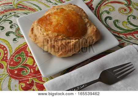 Nicely served single person breakfast of sweet pastry with fruit jam and a cup of hot tea on a colorful background
