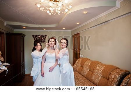 Bridesmaids Helping Dressed Bride On Wedding Day At Morning.