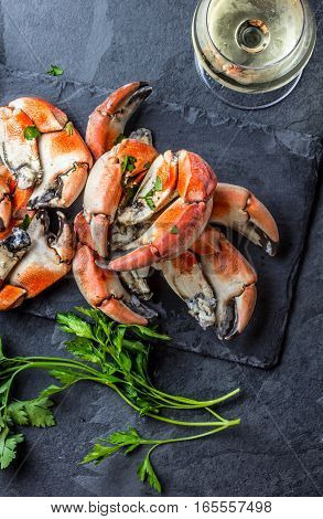Seafood. Crabs tentacles on black plate with wite wine, lemon and herbs sauce on slate background. Top view