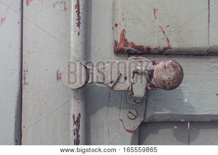 detail old wooden door safety lock, vintage painted covering wood, metal and screws. Timeworn paint