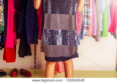 Little girl child choosing clothes to wear in wardrobe. Beautiful legs. Fashion clothing sale concept.