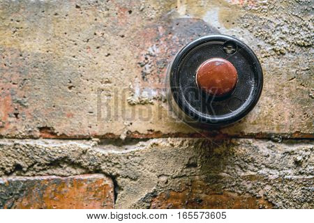 Old vintage door bell button on grunge brick wall
