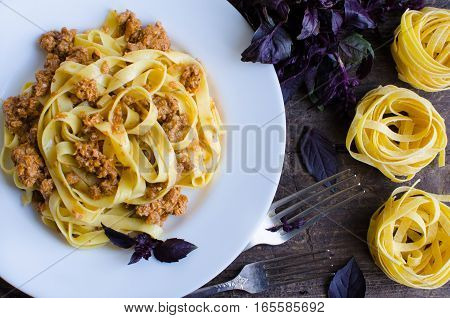 Tagliatelle with bolognese sauce on wooden background. Traditional Italian pasta Bolognaise with a spicy tomato based meat sauce garnished with fresh basil. Top view.
