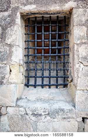 Barred window in the stone wall of the castle Santa Barbara, Alicante