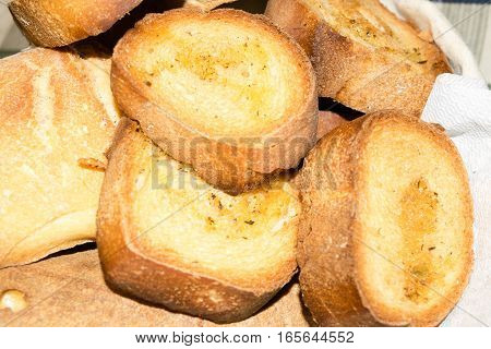 Basket filled with bread and slices of toasted bread seasoned with oil and pepper