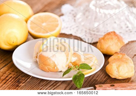 Lemon Profiteroles with custard cream on white dish.