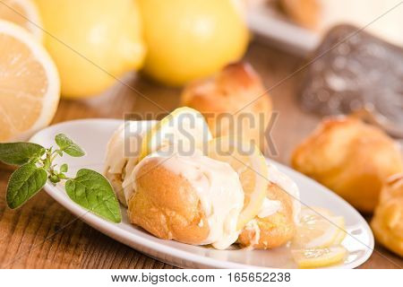 Lemon Profiteroles with custard cream on white dish.
