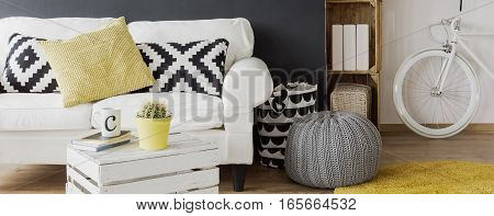 Cozy living room with white sofa pattern pillows DIY small table. pouffe and bike