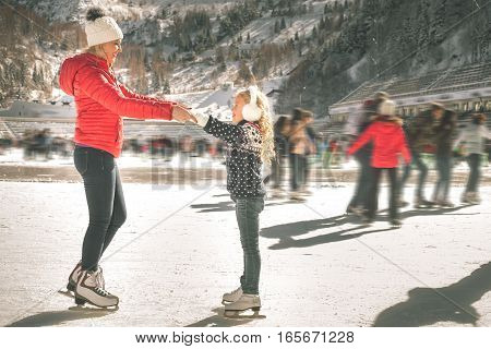 Happy family outdoor ice skating at rink. Mother and daughter has winter activities. Mom, kids. Medeo stadium. Almaty.