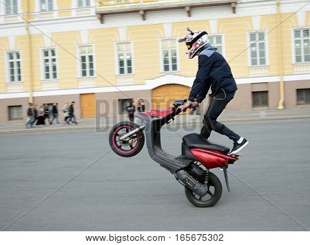 Reckless driver on the scooter performs complex and dangerous stunt.