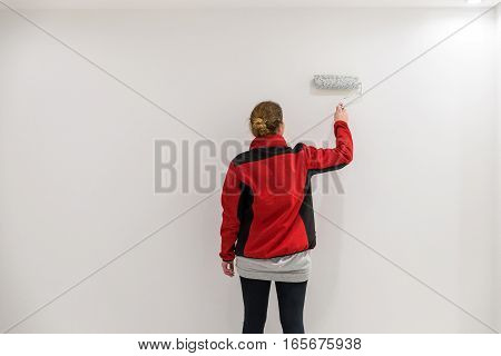 Female Painter With Paint Roller In Front Of Wall As Template