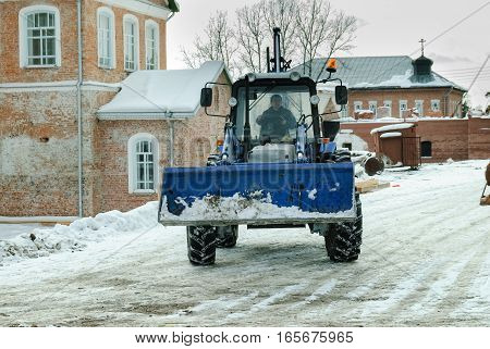 Priirtyshsky, Russia - May 2, 2010: Tractor with snowplowing equipment cleans road in Ioanno-Vvedensky female monastery. Tobolsk district