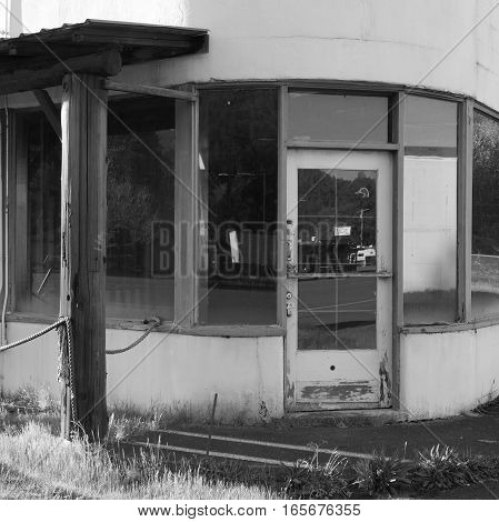 An old and abandoned building rounded on the corner with a door and several windows in the small town of Oakridge in Lane County in Western Oregon on a spring day.