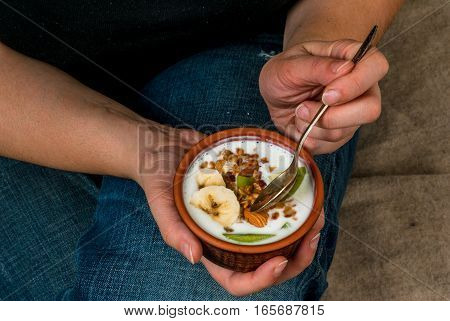 iet concept. Plus size (fat) girl eating diet and healthy breakfast: homemade yogurt with golden granola with nuts and fresh fruit (kiwi and banana)