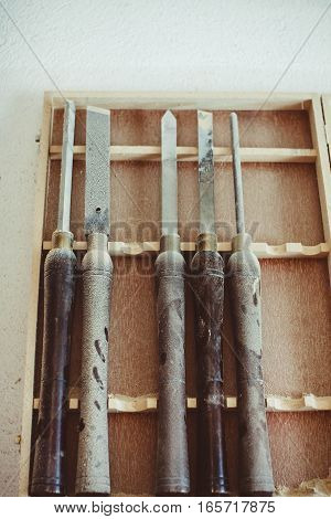 Old used wood lathe chisels selection on the dark wooden table, selective focus