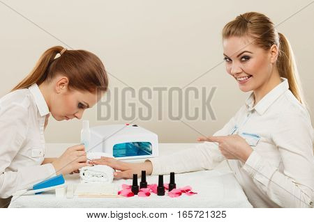 Relaxing time and wellness day concept. Blonde elegant woman visiting professional manicurist salon. Beautician makes perfect nails to client.