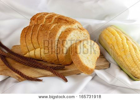bread made from corn on the white fabric. Slices of corn bread laying on a chopping Board and Sweet corn cobs